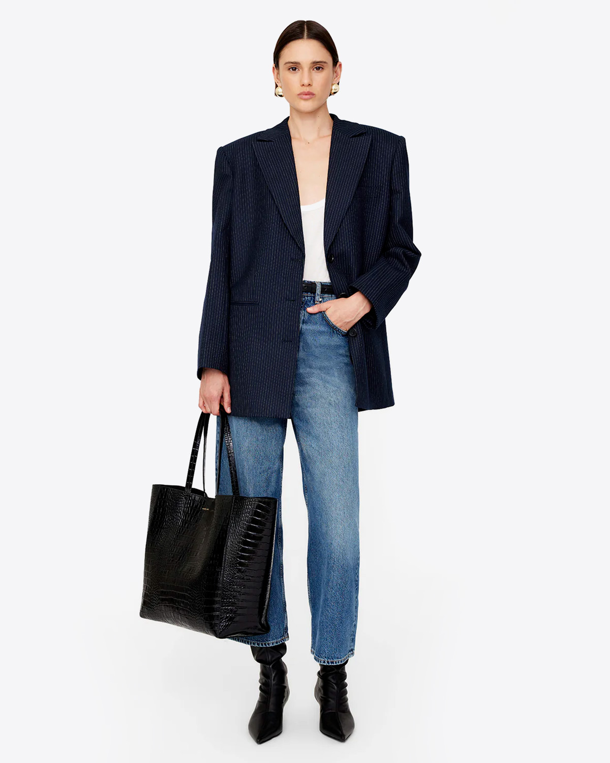 Sac Cabas Elly Anine Bing en cuir croco noir. Porté avec un blazer noir et un jean. 