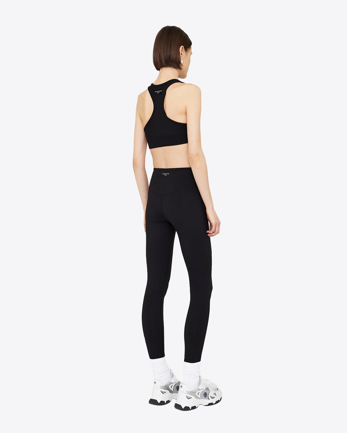 Legging stretch en polyamide et élasthanne noir mini logo AB devant Blake Anine Bing. Porté de dos avec une brassière assortie.