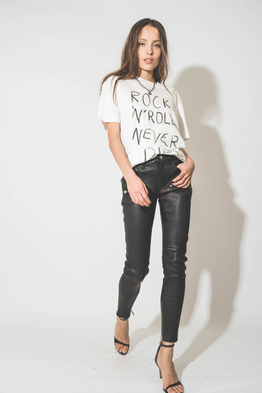 Pantalon skinny en cuir noir avec des zips aux poches et bas de jambes Remy Anine Bing. Porté avec un tee-shirt blanc Rock.