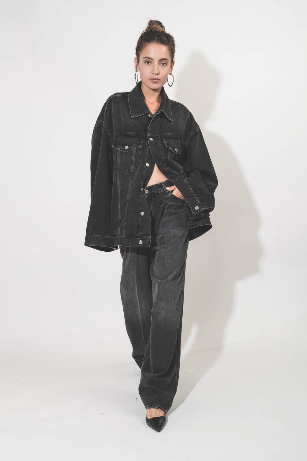 Blouson oversized en jean noir délavé en Lyocell fluide Janet Haikure. Porté avec des créole en métal argenté.