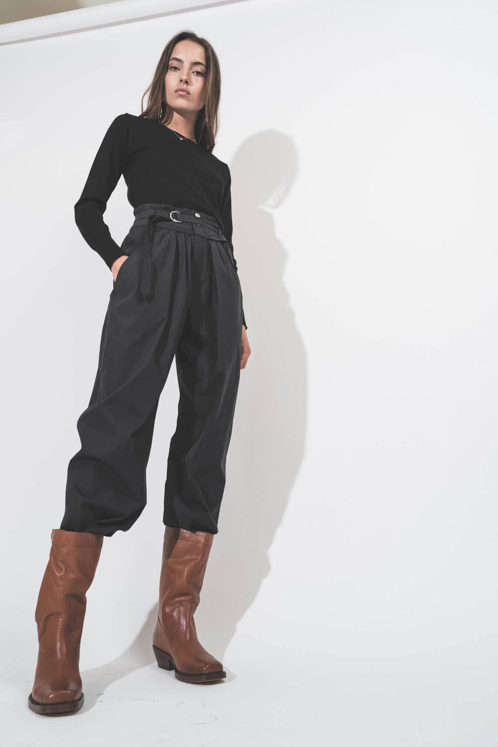 Pantalon large taille haute en toile noire avec ceinture Célia Isabel Marant Etoile. Porté avec des boots en cuir Havana.